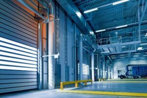 Interior de um centro logístico iluminado, com portas industriais e equipamentos, simbolizando empresas e indústrias