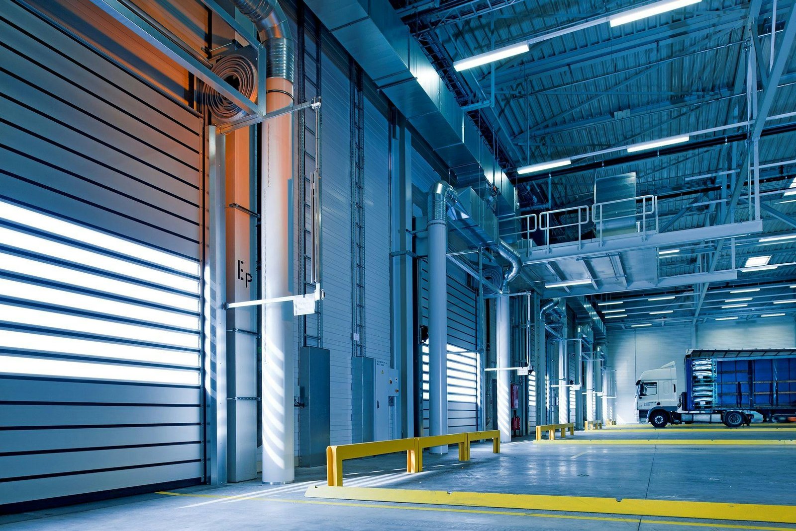 Interior de um centro logístico iluminado, com portas industriais e equipamentos, simbolizando empresas e indústrias