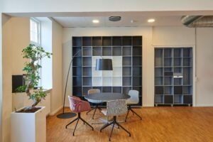 Ambiente de escritório moderno com mesa redonda, cadeiras e estante ao fundo, representando o setor de comércios e escritórios
